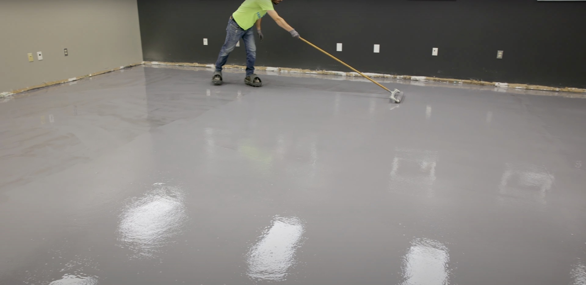 Commercial concrete floor coating and finishing work Worker applying concrete floor coating with professional equipment in commercial space