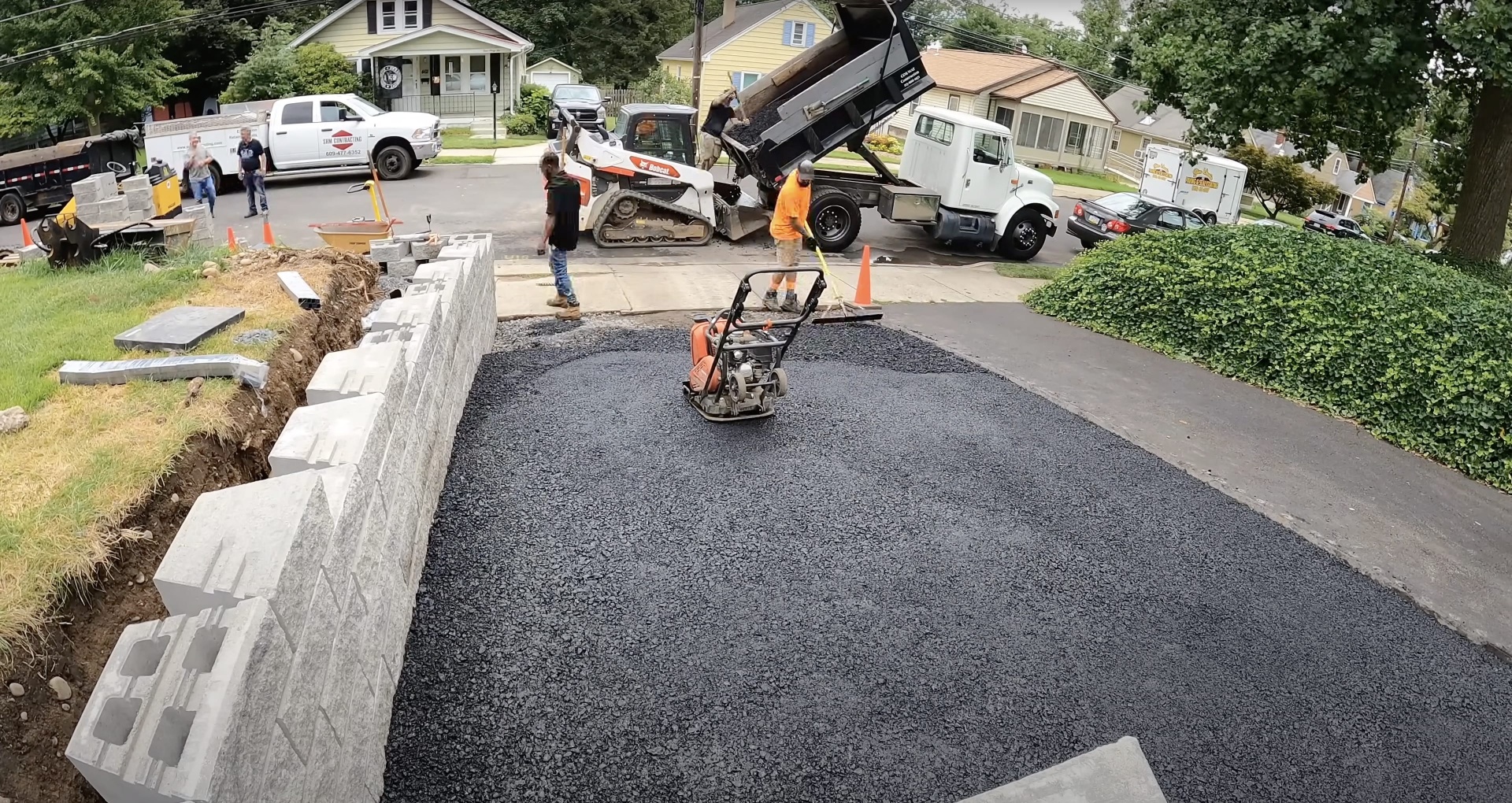 Driveway installation with concrete borders and professional paving Asphalt driveway installation with concrete curbing and professional equipment